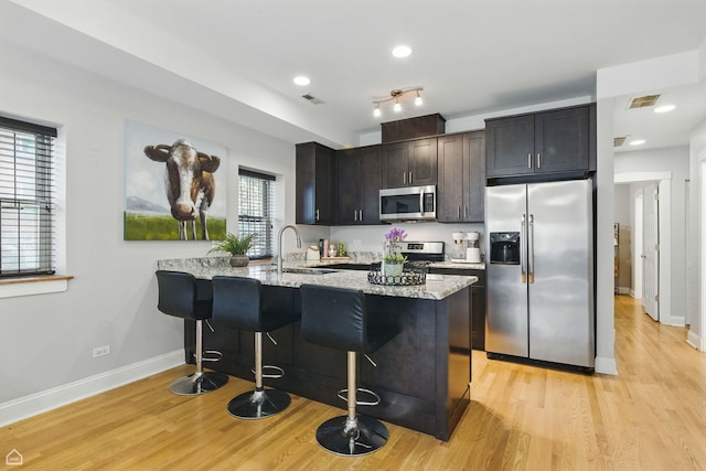 4857 N Drake Ave Unit G, Chicago, IL 60625 - kitchen with appliances with stainless steel finishes, light wood finished floors, a peninsula, light stone countertops, and a kitchen breakfast bar