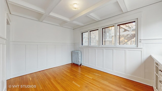 1646 E 54th St Unit 2, Chicago, IL 60615 - empty room featuring radiator, coffered ceiling, a decorative wall, beamed ceiling, and light wood-style floors