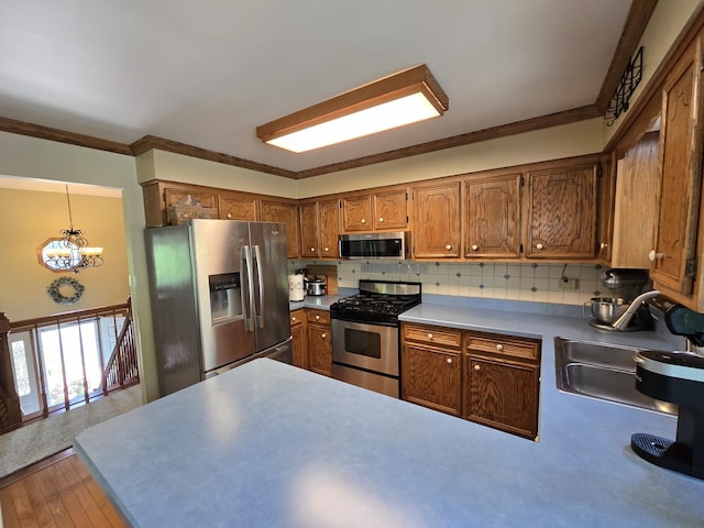 4910 143rd Pl, Midlothian, IL 60445 - kitchen featuring stainless steel appliances, a chandelier, brown cabinetry, a peninsula, and crown molding