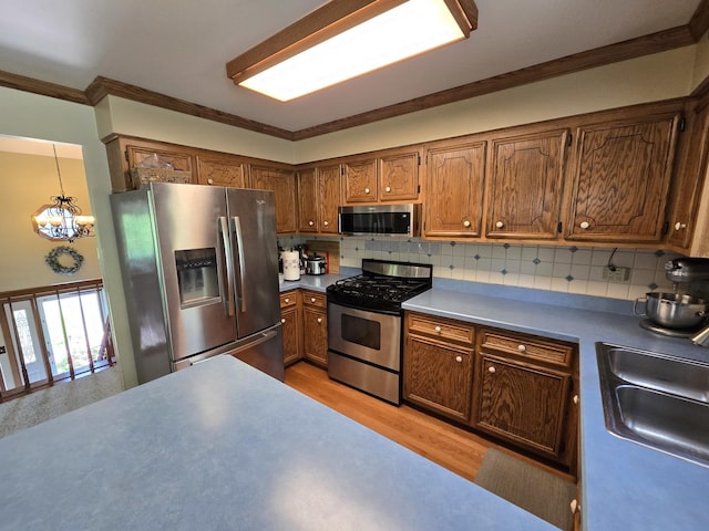 4910 143rd Pl, Midlothian, IL 60445 - kitchen featuring appliances with stainless steel finishes, a chandelier, brown cabinetry, light wood finished floors, and crown molding