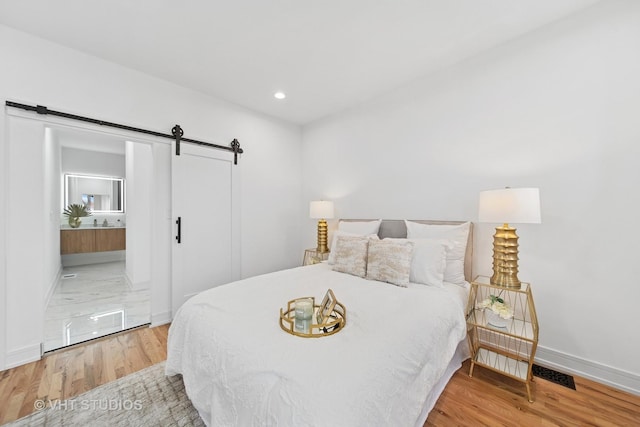 4752 S Champlain Ave, Chicago, IL 60615 - bedroom featuring a barn door, baseboards, wood finished floors, recessed lighting, and ensuite bath