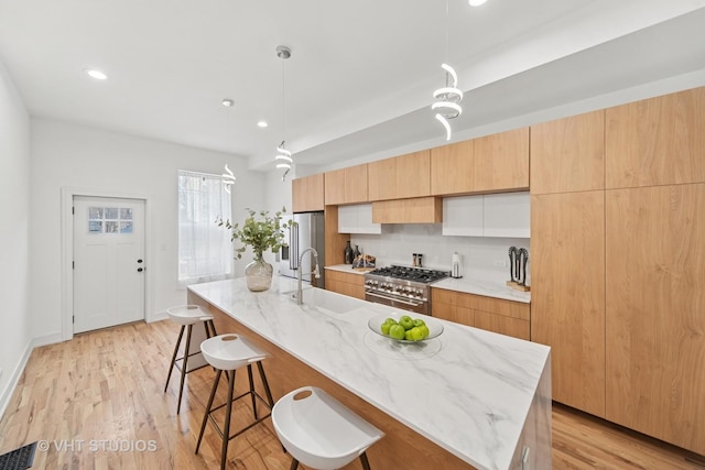 4752 S Champlain Ave, Chicago, IL 60615 - kitchen with a sink, stainless steel appliances, a kitchen breakfast bar, a kitchen island with sink, and light wood-type flooring