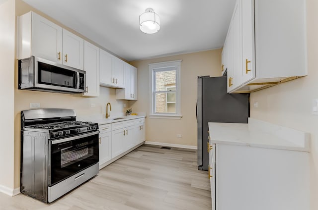 7955 S May St, Chicago, IL 60620 - kitchen with stainless steel appliances, a sink, white cabinets, light wood-style floors, and baseboards