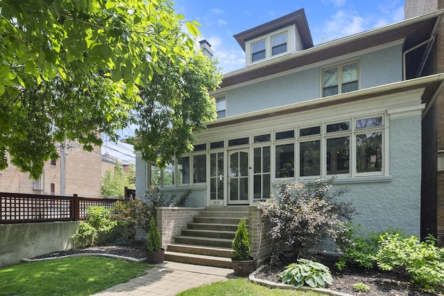 1419 W Birchwood Ave, Chicago, IL 60626 - view of front of home featuring a sunroom, stucco siding, entry steps, and a chimney