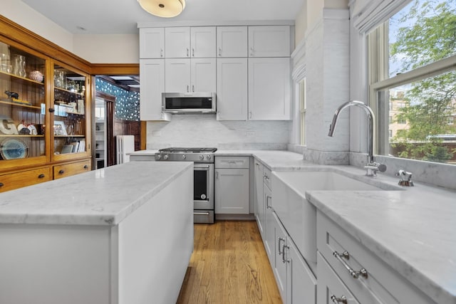 1419 W Birchwood Ave, Chicago, IL 60626 - kitchen featuring appliances with stainless steel finishes, light wood-type flooring, light stone counters, and decorative backsplash