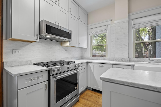 1419 W Birchwood Ave, Chicago, IL 60626 - kitchen featuring stainless steel appliances, light stone counters, white cabinetry, backsplash, and light wood-type flooring