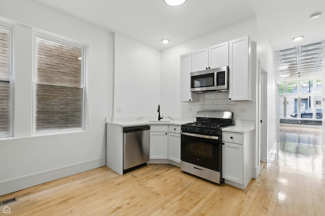 1928 W 21st St, Chicago, IL 60608 - kitchen featuring appliances with stainless steel finishes, light wood-style flooring, recessed lighting, white cabinetry, and decorative backsplash
