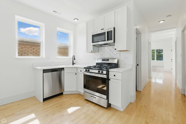 1928 W 21st St, Chicago, IL 60608 - kitchen featuring appliances with stainless steel finishes, light wood-style floors, light countertops, white cabinets, and tasteful backsplash