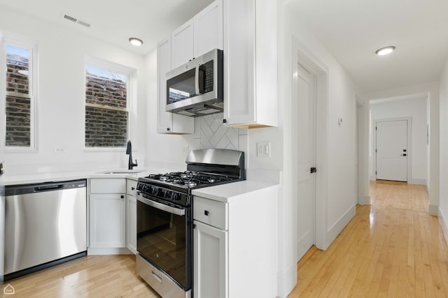1928 W 21st St, Chicago, IL 60608 - kitchen featuring appliances with stainless steel finishes, light wood-style floors, backsplash, and white cabinetry