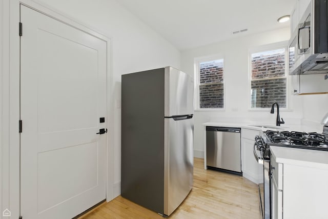 1928 W 21st St, Chicago, IL 60608 - kitchen with stainless steel appliances, light wood-style flooring, light countertops, white cabinetry, and vaulted ceiling