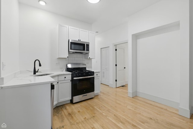 1928 W 21st St, Chicago, IL 60608 - kitchen featuring stainless steel microwave, gas stove, light wood-style flooring, tasteful backsplash, and white cabinets
