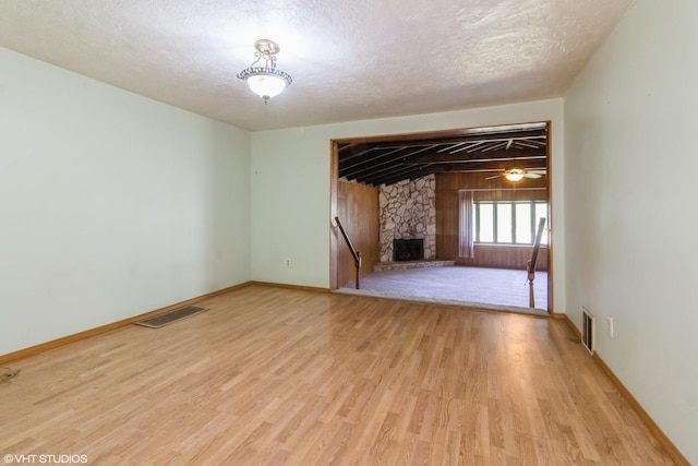 509 Sherman Ave, Aurora, IL 60505 - empty room featuring light wood finished floors, a stone fireplace, and a textured ceiling