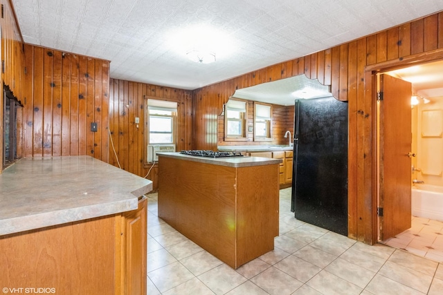 509 Sherman Ave, Aurora, IL 60505 - kitchen featuring freestanding refrigerator, wooden walls, a kitchen island, stainless steel gas cooktop, and light countertops