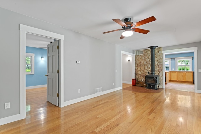 1046 N Riverside Dr, Momence, IL 60954 - unfurnished living room with a wood stove, light wood finished floors, healthy amount of natural light, and ceiling fan