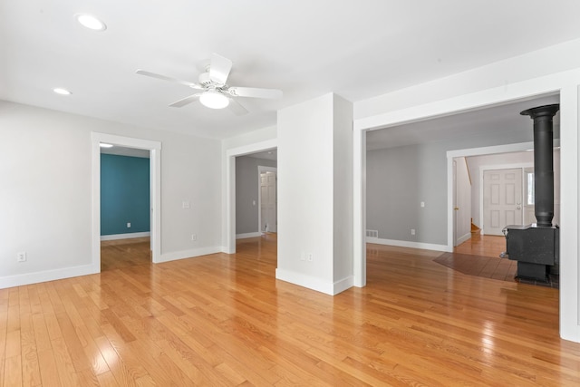 1046 N Riverside Dr, Momence, IL 60954 - unfurnished living room featuring a wood stove, a ceiling fan, light wood-style floors, and recessed lighting