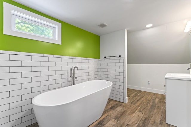1046 N Riverside Dr, Momence, IL 60954 - bathroom with tile walls, vanity, a soaking tub, wood finished floors, and a wainscoted wall
