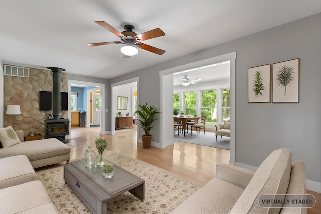 1046 N Riverside Dr, Momence, IL 60954 - living area featuring a wood stove, a ceiling fan, and light wood-style flooring