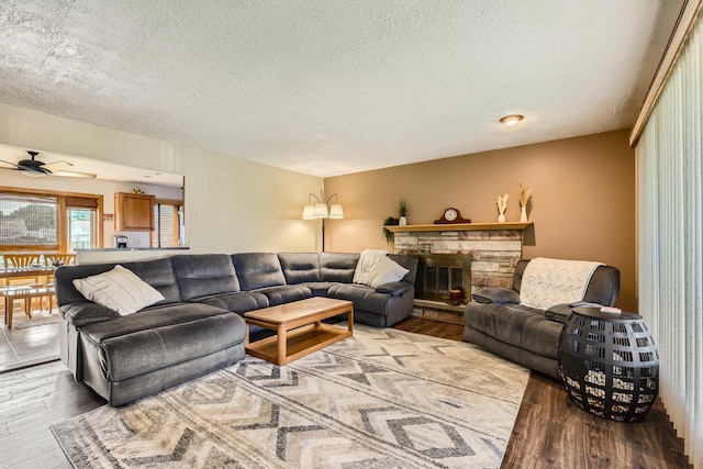 9001 Mobile Ave, Oak Lawn, IL 60453 - living room with wood finished floors, a textured ceiling, ceiling fan, and a stone fireplace