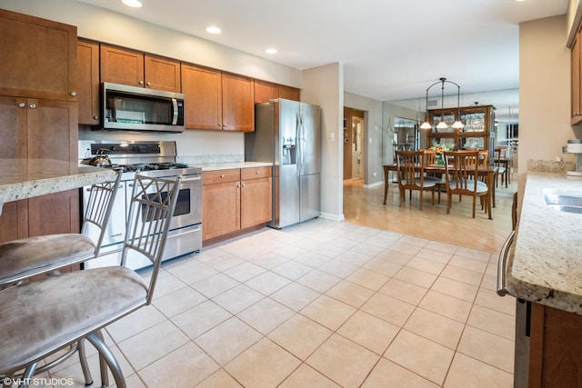 10901 W 131st St, Orland Park, IL 60467 - kitchen featuring appliances with stainless steel finishes, brown cabinets, light stone countertops, recessed lighting, and light tile patterned floors