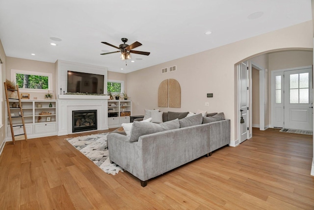20111 N Woodland Cir, Mokena, IL 60448 - living room featuring arched walkways, a ceiling fan, light wood-style flooring, a glass covered fireplace, and recessed lighting