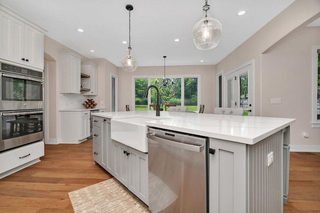 20111 N Woodland Cir, Mokena, IL 60448 - kitchen with stainless steel appliances, light wood finished floors, a center island with sink, recessed lighting, and white cabinets