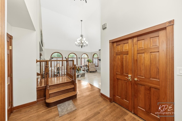 645 Saint Christopher Ct, Aurora, IL 60506 - hallway with wood finished floors, a chandelier, a towering ceiling, and stairs