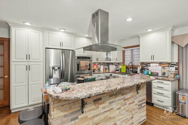 645 Saint Christopher Ct, Aurora, IL 60506 - kitchen with island exhaust hood, stainless steel appliances, a breakfast bar, backsplash, and white cabinetry