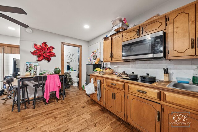 645 Saint Christopher Ct, Aurora, IL 60506 - kitchen featuring stainless steel microwave, black electric stovetop, ceiling fan, backsplash, and light wood-style flooring