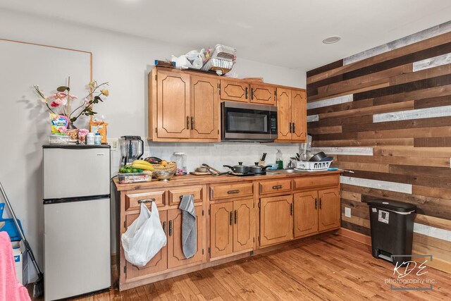 645 Saint Christopher Ct, Aurora, IL 60506 - kitchen featuring stainless steel microwave, freestanding refrigerator, wood walls, light wood-style floors, and decorative backsplash