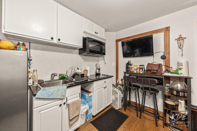 645 Saint Christopher Ct, Aurora, IL 60506 - kitchen with freestanding refrigerator, black microwave, white cabinetry, light wood finished floors, and dark countertops