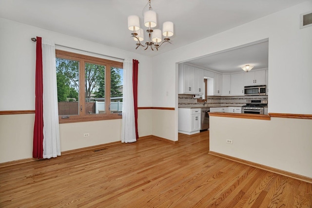 8932 Pebble Beach Ln, Orland Park, IL 60462 - kitchen featuring stainless steel appliances, light wood-style flooring, a chandelier, white cabinets, and decorative backsplash