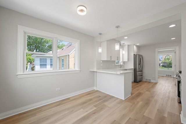 7810 N Neva Ave, Niles, IL 60714 - kitchen featuring appliances with stainless steel finishes, light countertops, light wood-style flooring, white cabinets, and tasteful backsplash