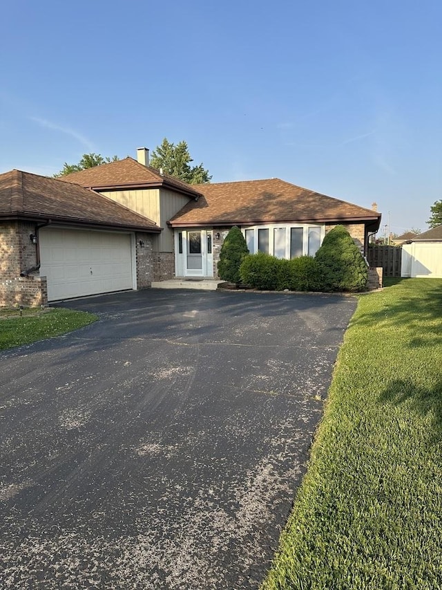 19205 Ada St, Lansing, IL 60438 - view of front facade with driveway, an attached garage, a chimney, and brick siding