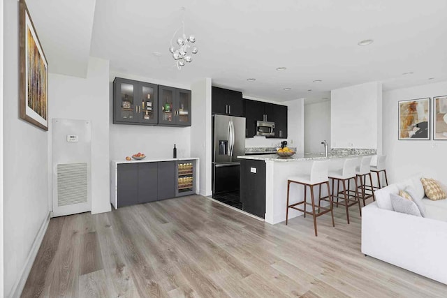 737 W Washington Blvd Unit 3308, Chicago, IL 60661 - kitchen featuring appliances with stainless steel finishes, a kitchen bar, dark cabinetry, wine cooler, and light wood-style floors