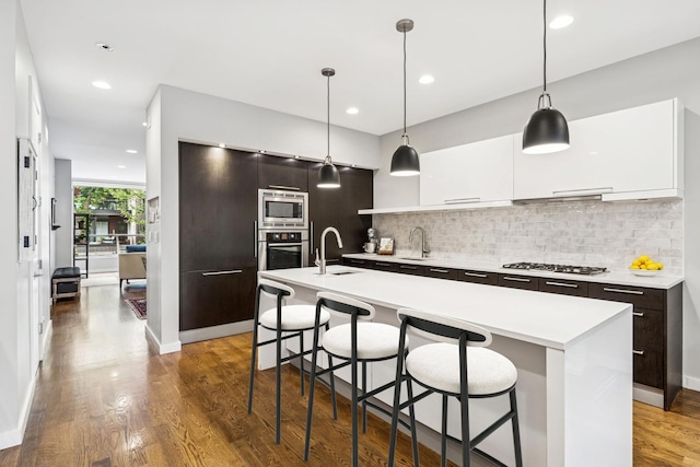 874 N Marshfield Ave Unit 1, Chicago, IL 60622 - kitchen featuring stainless steel appliances, modern cabinets, light countertops, tasteful backsplash, and a kitchen bar