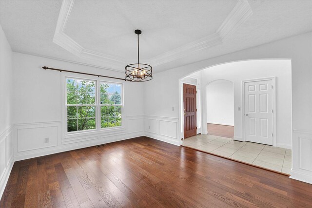1904 Mullikin Dr, Champaign, IL 61822 - empty room with a tray ceiling, hardwood / wood-style flooring, arched walkways, a chandelier, and crown molding