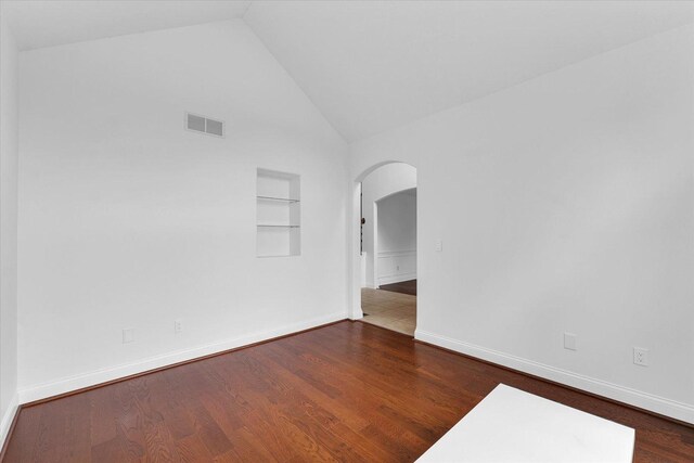 1904 Mullikin Dr, Champaign, IL 61822 - empty room featuring built in shelves, arched walkways, wood finished floors, and high vaulted ceiling