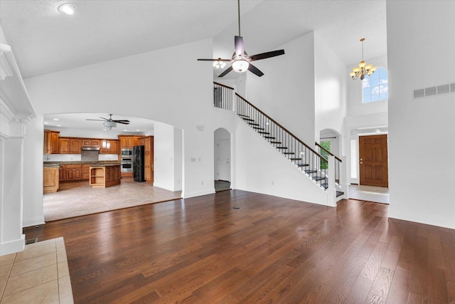 1904 Mullikin Dr, Champaign, IL 61822 - unfurnished living room featuring ceiling fan, high vaulted ceiling, arched walkways, hardwood / wood-style flooring, and stairs