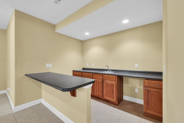 1904 Mullikin Dr, Champaign, IL 61822 - kitchen featuring dark countertops, a peninsula, a kitchen bar, light tile patterned flooring, and recessed lighting