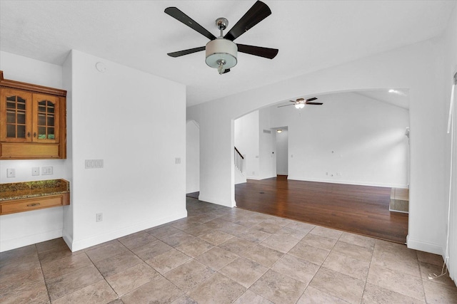 1904 Mullikin Dr, Champaign, IL 61822 - empty room featuring ceiling fan, arched walkways, stairs, and light stone finish floors