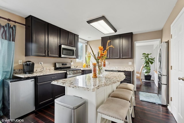 2855 Weld Rd, Elgin, IL 60124 - kitchen with stainless steel appliances, dark wood finished floors, a kitchen breakfast bar, a kitchen island, and light stone countertops
