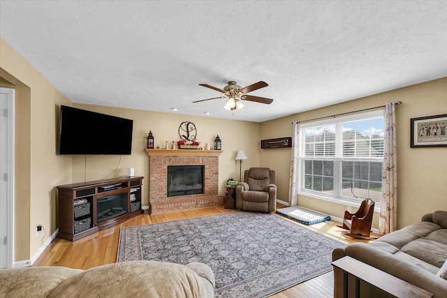 3911 Tallgrass Dr, Champaign, IL 61822 - living room featuring wood finished floors, a ceiling fan, a textured ceiling, and a brick fireplace