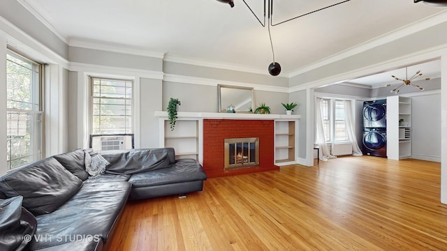 117 S Grove Ave, Oak Park, IL 60302 - living area with stacked washing machine and dryer, light wood-style floors, a fireplace, a chandelier, and crown molding