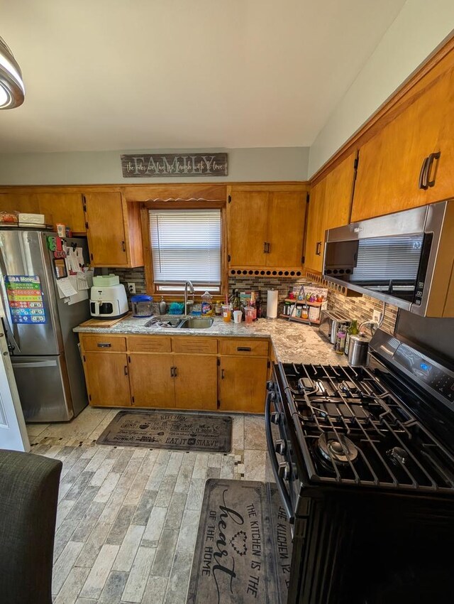 kitchen featuring appliances with stainless steel finishes, light wood-style floors, light countertops, and brown cabinetry