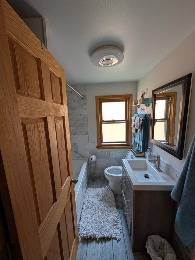 full bath with vanity, tile walls, bathing tub / shower combination, and wood finished floors