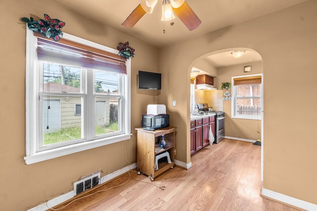 3914 Madison St, Bellwood, IL 60104 - kitchen with stainless steel gas stove, black microwave, arched walkways, light wood-style flooring, and a ceiling fan