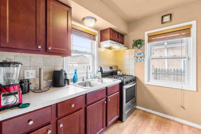 3914 Madison St, Bellwood, IL 60104 - kitchen with stainless steel range with gas cooktop, under cabinet range hood, light countertops, light wood-style flooring, and tasteful backsplash