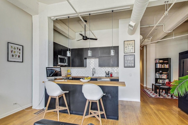 124 W Polk St Unit 603, Chicago, IL 60605 - kitchen featuring butcher block counters, stainless steel microwave, a breakfast bar, decorative backsplash, and light wood-style flooring