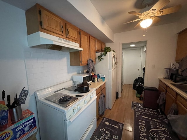 786 Delmar Ct Unit 6, University Park, IL 60484 - kitchen with under cabinet range hood, white appliances, tasteful backsplash, light countertops, and brown cabinetry