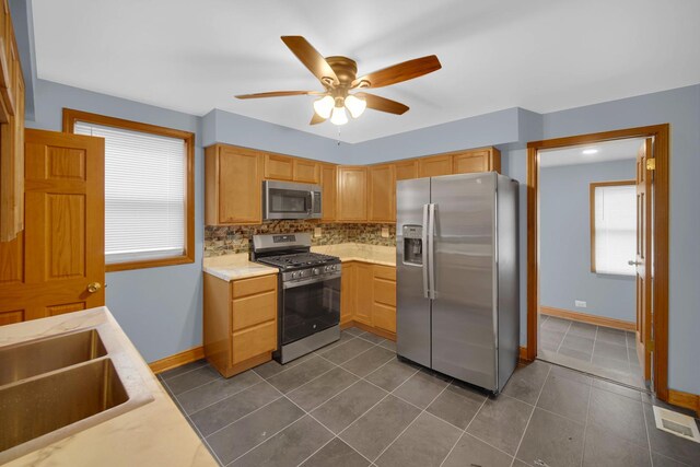 1515 E 85th St, Chicago, IL 60619 - kitchen featuring appliances with stainless steel finishes, ceiling fan, tasteful backsplash, light countertops, and dark tile patterned flooring